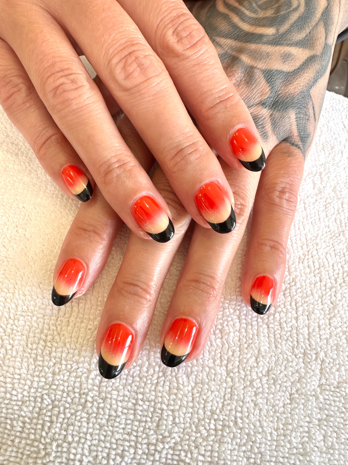Oval nails in a red to nude ombre with glossy black French tips